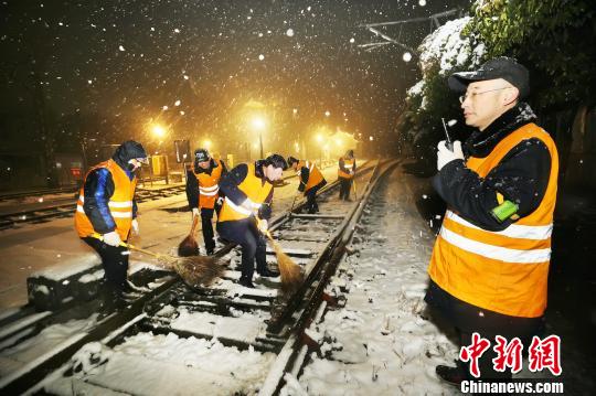 1月30日晚，苏皖地区降雪，徐州机务段干部职工连夜清除机车整备场道岔上的积雪。　李文伟 摄