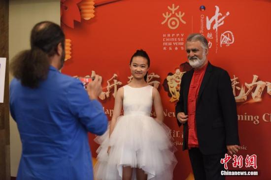 在春节即将到来之际，当地时间1月30日晚，2019“欢乐春节·魅力中国”晚会在美国洛杉矶举行，为中美各界嘉宾带来一场精彩的文艺盛宴。14岁的北京女孩李溯（图中）是这场晚会最年轻的小演员，她精湛的钢琴独奏赢得全场掌声。图为身着红色唐装的美国与会嘉宾热情地同来自中国的李溯在晚会现场合影。<a target='_blank'  data-cke-saved-href='http://www.chinanews.com/' href='http://www.chinanews.com/'>中新社</a>记者 张朔 摄