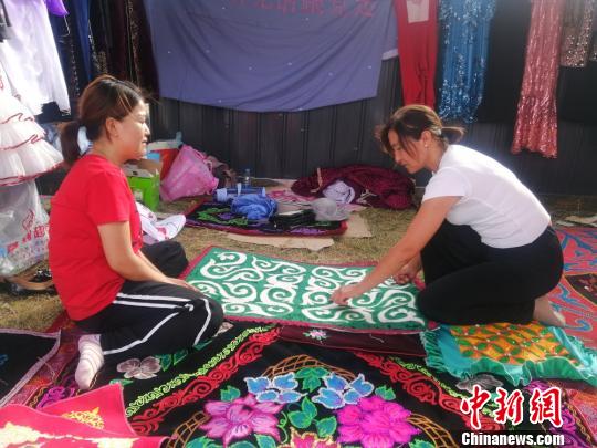 四川游客张晓勤向刺绣展商了解哈萨克族刺绣文化。　古丽米娜 摄