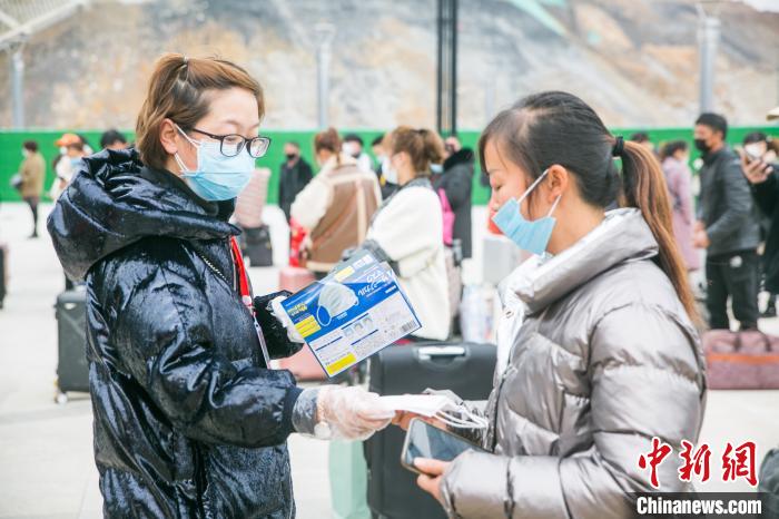 2月20日，在贵州省毕节市大方站，工作人员正在为返岗农民工发放备用口罩。　罗大富 摄