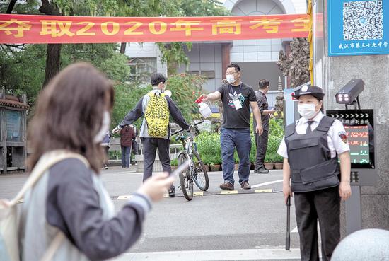 5月6日，武汉市第三十九中学门口，老师在给一名入校的高三学生喷消毒液。当日，武汉教育、公安、卫生、城管、街道等部门已为全市复课学校从学、行、住、吃、医等方面，做好安全准备。 （湖北日报全媒记者 魏铼 通讯员 孙逊 摄）