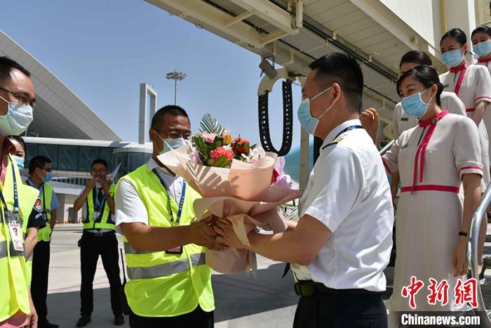 6月5日12时35分，长龙航空执飞的西安—库尔勒首航飞机平稳降落在库尔勒机场，库尔勒机场相关负责同志正在给机长献花。　景丽君 摄