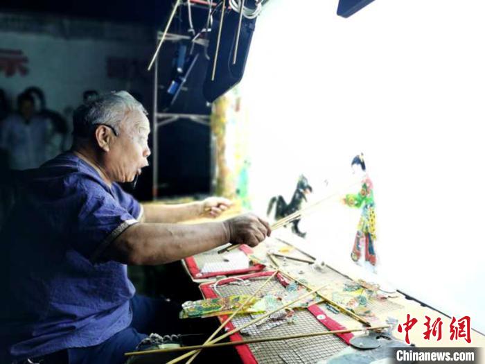 图为国家级非物质文化遗产泰山皮影戏的传承人范正安在12日晚表演皮影，为活动预热。　攒文 摄