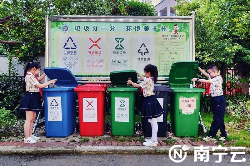 江南区富乐小学的学生将垃圾分类后放入垃圾桶。黄维业
