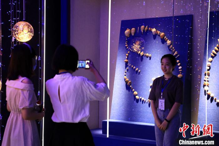 7月16日，在山东博物馆举办的“三千玲珑——中国海洋贝类展”上，参观者在贝壳拼接成的翅膀造型前拍照留念。　李欣 摄