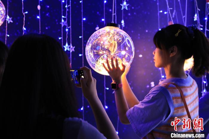 7月16日，在山东博物馆举办的“三千玲珑——中国海洋贝类展”上，参观者在贝灯区域打卡留念。　李欣 摄